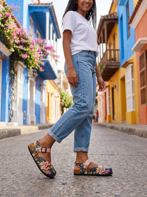 Calceo.co dark blue clogs with pink roses, orange flowers, and green leaves pattern. Features adjustable strap and cork sole.