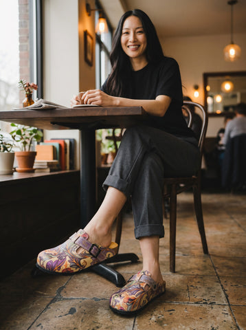 Calceo.co clogs with purple, pink, orange floral and green leaf pattern. Adjustable strap, cork sole, artificial leather and cotton canvas.